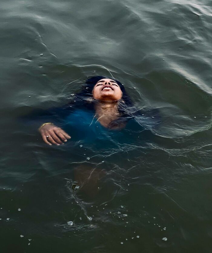 Woman swimming in dark water captured in an artistic photography page showcasing explore Asia travel moments