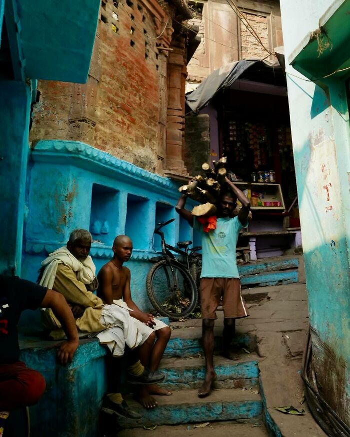Men resting on blue painted steps in an Asian street scene, showcasing vibrant local culture and daily life photography.