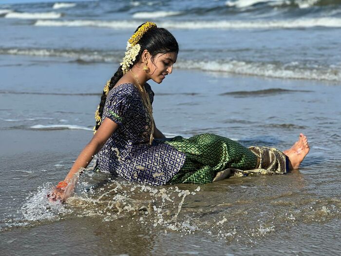 Young girl in traditional attire playing in the water at the beach, capturing the essence of exploring Asia photography.