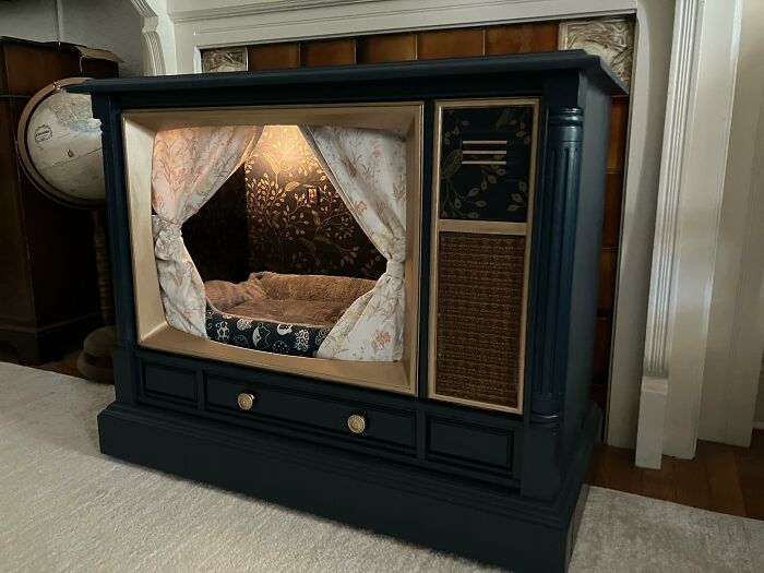 Vintage TV repurposed into a cozy cat bed with curtains and soft bedding inside, showcasing nostalgic nooks for pets.