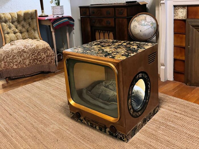 Vintage TV repurposed into a cozy cat bed with floral patterns, placed in a nostalgic, vintage-style living room.