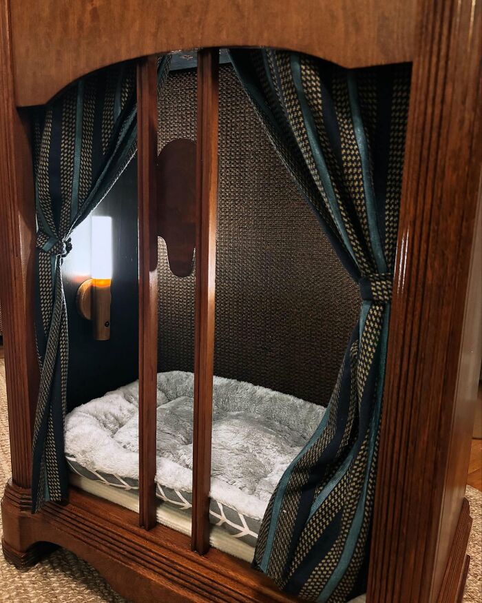 Vintage TV repurposed as a cozy cat bed with plush cushion and curtains, creating a nostalgic nook for pets.