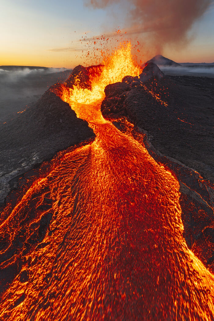 Lava flow erupting from a volcano at sunset captured in a dramatic aerial shot showcasing intense natural energy.