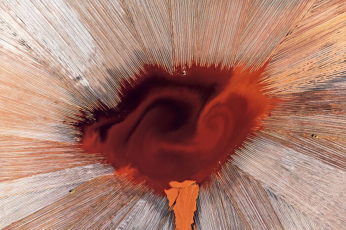 Aerial shot of vibrant red and orange patterns resembling a swirling natural formation, captured by an international photographer.