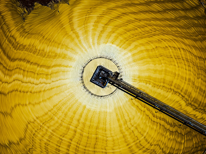 Aerial shot of a circular structure with a long arm casting shadows, showcasing winning aerial photography skills.