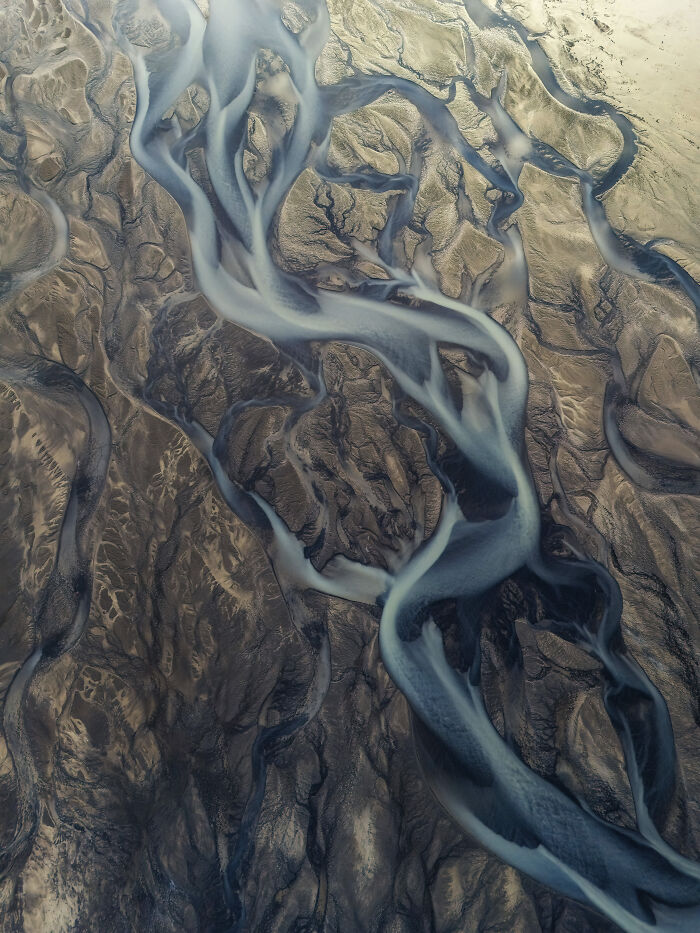 Aerial view of winding river channels over a textured landscape, showcasing winning aerial shots by a top international photographer.