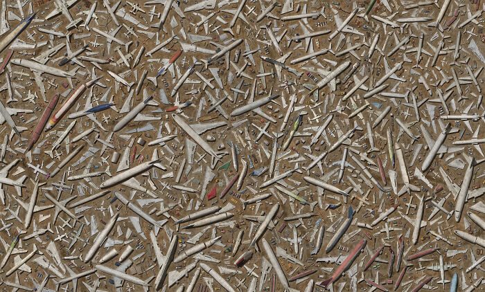 Aerial view of numerous airplanes parked closely together in a large airplane graveyard with faded colors.