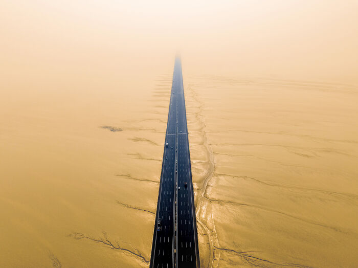 Aerial shot of a long highway disappearing into desert fog, showcasing winning aerial shots from the International Photographer.