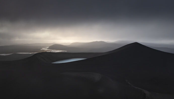 Dark volcanic landscape with mist and water pools captured in a winning aerial shot from the International Photographer of the Year 2025.