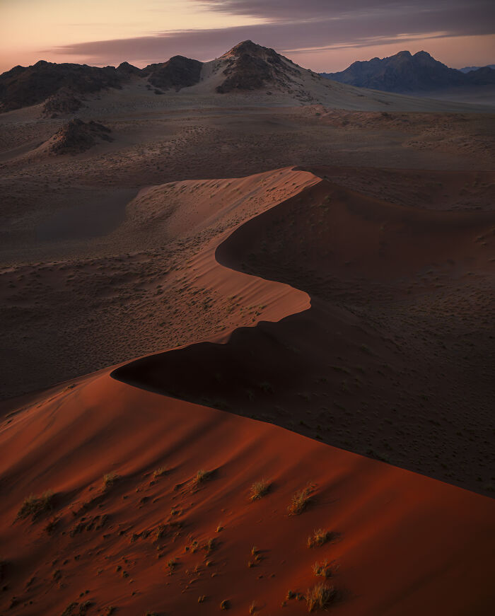 Aerial shot of vast red sand dunes at sunset showcasing stunning desert landscape and natural patterns.
