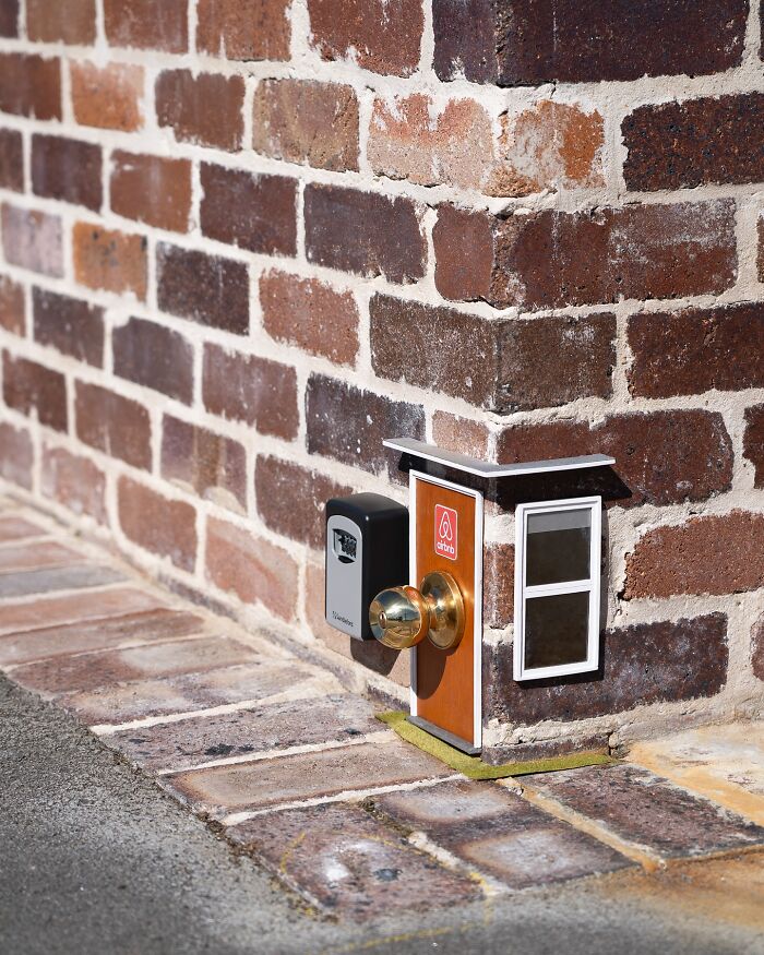 Tiny street scene featuring a miniature door and mailbox built into a brick wall, showcasing funny street art in the city.