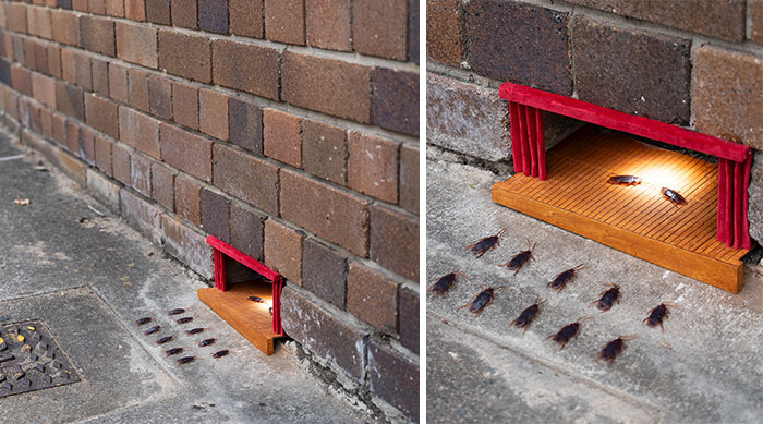 Tiny street scene of a miniature stage set into a brick wall sidewalk with small cockroach audience around it.