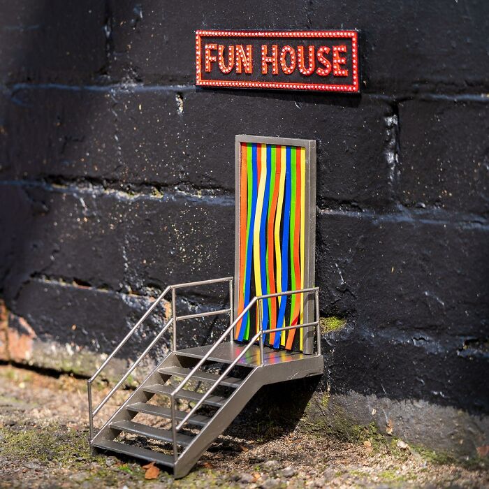 Miniature funny tiny street scene of a colorful fun house entrance with stairs on a city wall.