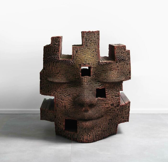 Hypnotic 3D face sculpture made from wooden sticks with textured and blocky design, appearing lifelike and artistic.