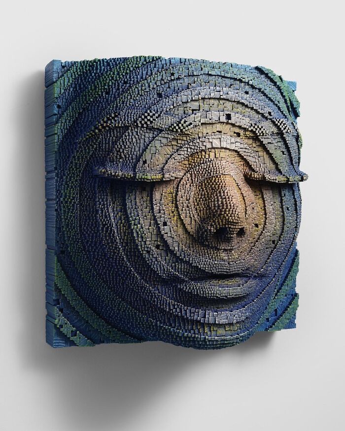 3D wooden face sculpture made from stacked wooden sticks showing hypnotic depth and intricate texture.
