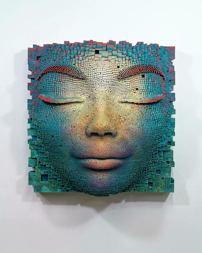 Hypnotic 3D face sculpture made from wooden sticks, showcasing intricate textures and vibrant blue and orange colors.