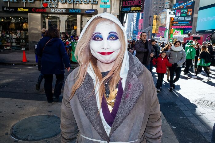Street photo of a person in theatrical makeup walking in a busy NYC street, showcasing NYC's endless stories.