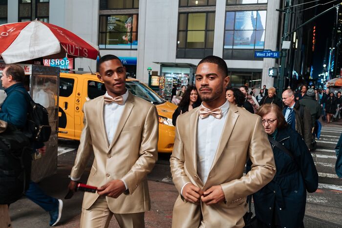 Two men in gold suits and bow ties walking on a busy NYC street, showcasing vibrant street photos and city life.