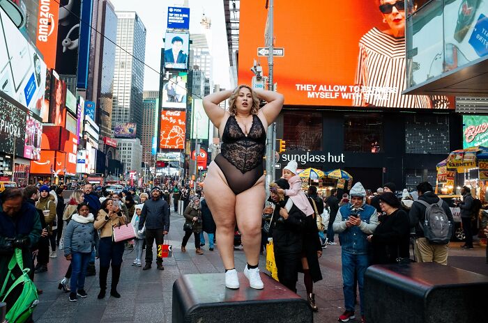 Curvy woman posing confidently in Times Square amid crowds, showcasing powerful street moments of NYC photography.