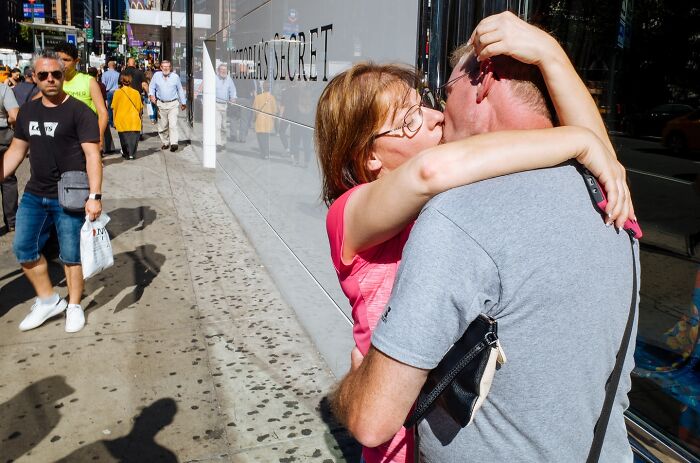 Couple sharing a passionate kiss on a busy NYC street captured in powerful street moments photography.