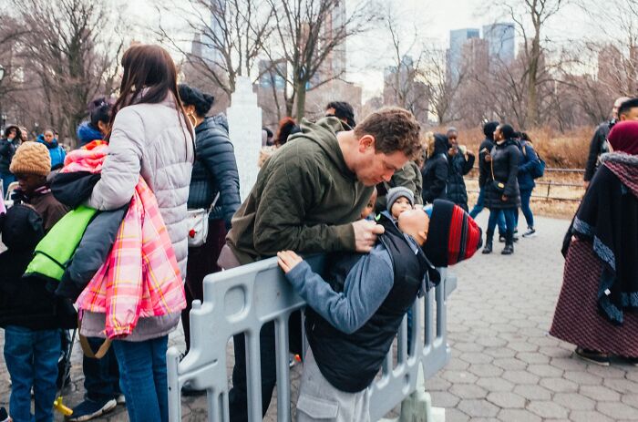 Man and child sharing a moment in a lively NYC street scene, capturing striking street photos of city life.