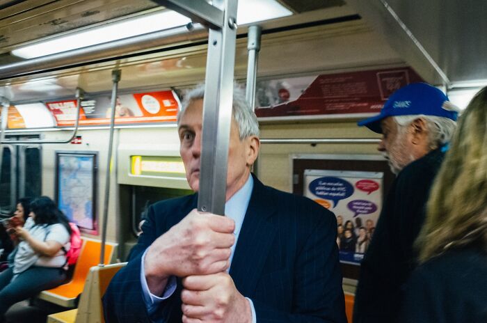 Man gripping pole inside crowded NYC subway, capturing a powerful street moment in New York City public transit.