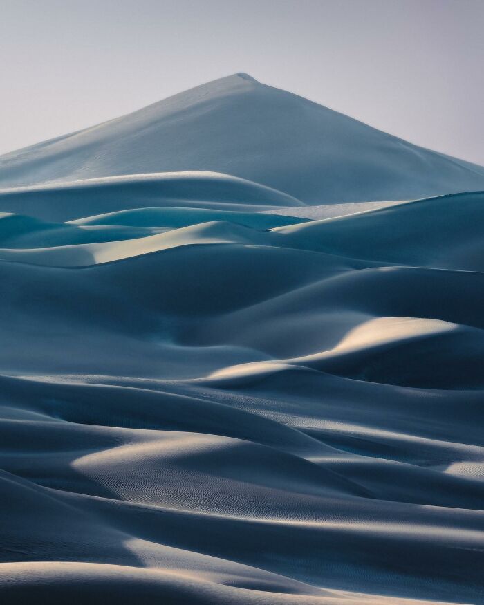 Vast breathtaking landscape of smooth sand dunes with soft light, evoking a scene straight out of a fantasy movie.