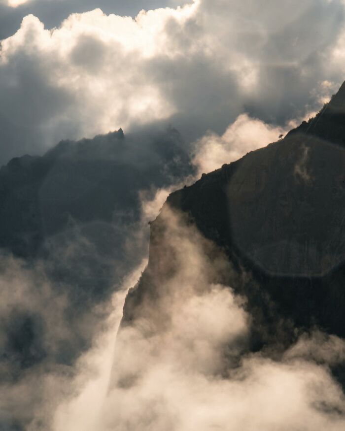 Photographer captured breathtaking landscape shots of misty mountain peaks surrounded by dramatic clouds, resembling fantasy movie scenes.