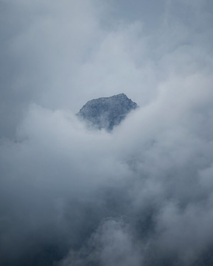 Mountain peak emerging from thick clouds in a breathtaking landscape shot that looks straight out of a fantasy movie.