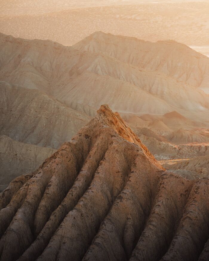 Breathtaking landscape shot of rugged mountain ridges bathed in warm light, resembling a scene from a fantasy movie.