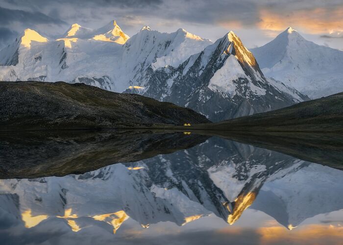 Snow-capped mountains reflected in a still lake, showcasing breathtaking landscape shots resembling a fantasy movie scene.