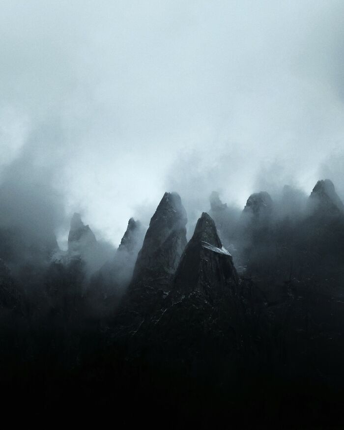 Dark jagged mountain peaks shrouded in mist, creating breathtaking landscape shots with a fantasy movie atmosphere.