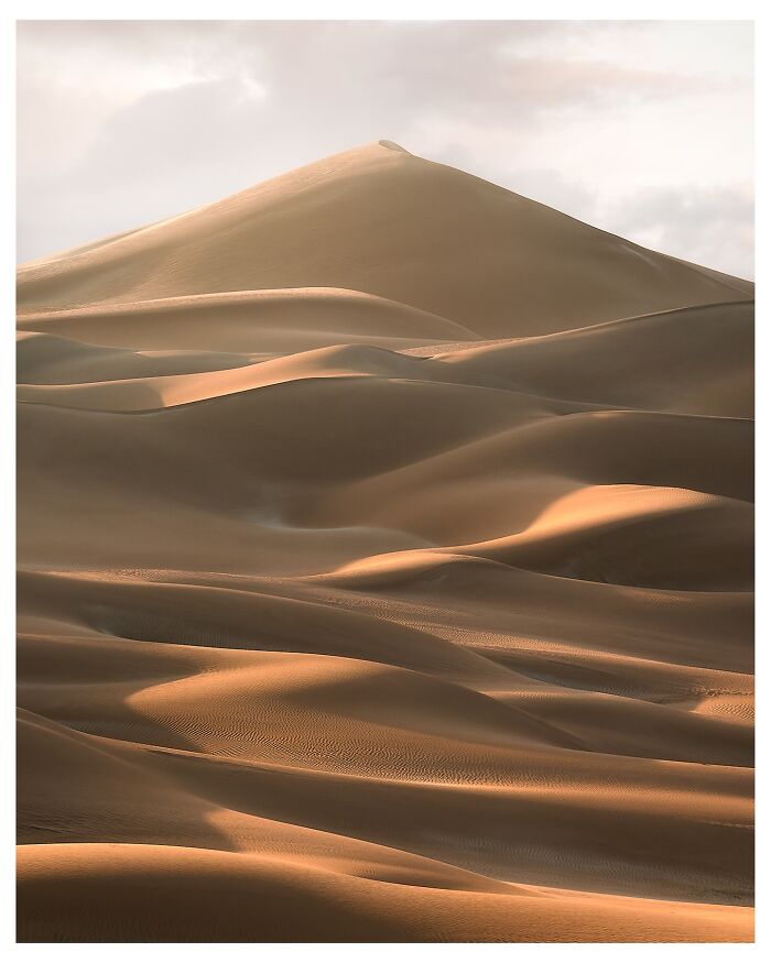 Breathtaking landscape shot of smooth sand dunes glowing in soft light, resembling a fantasy movie setting.
