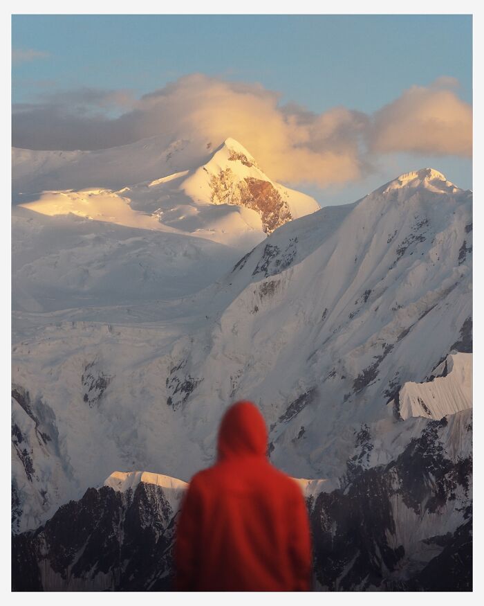 Person in a red jacket admiring breathtaking snowy mountain landscape shots that look like scenes from a fantasy movie.
