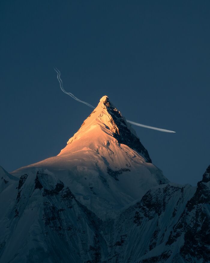 Snow-covered mountain peak illuminated by golden light with clear dark sky, showcasing breathtaking landscape photography.