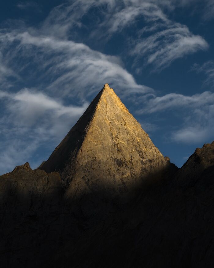 Breathtaking landscape photo of a sharp mountain peak illuminated by sunlight against a dramatic cloudy sky.