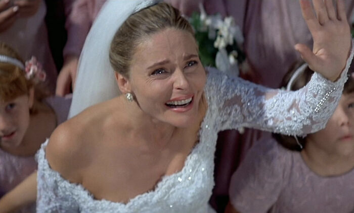 Bond Girl in wedding dress with lace sleeves reaching out emotionally in a dramatic film scene with children around her. Bond Girl in wedding dress with lace sleeves reaching out emotionally in a dramatic film scene with children around her.