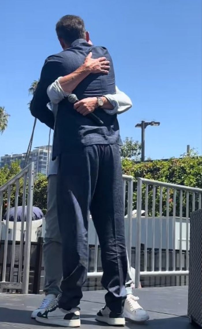 Two Harry Potter stars hugging warmly outdoors during a surprise reunion that excites fans under a clear blue sky.