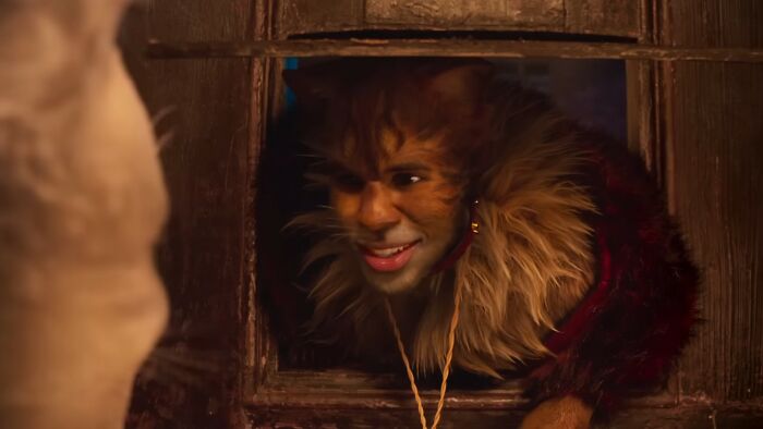Man in a fur costume smiling through a wooden window frame in a scene from one of the worst movies of all time.