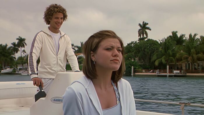 Two young people on a boat with a waterfront backdrop, representing scenes from worst movies of all time.