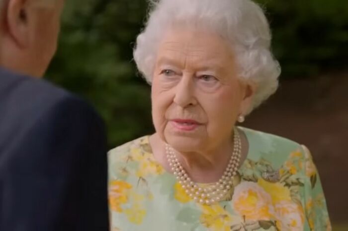 Elderly woman in floral dress and pearl necklace speaking to a man outdoors, highlighting small daily feminist wins.