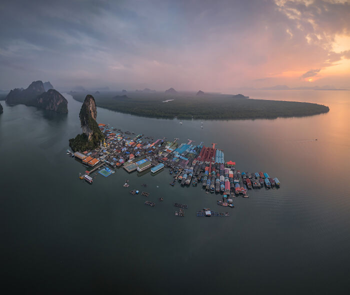 Aerial view of a coastal village surrounded by mangroves and calm waters at sunset, highlighting mangrove photography.