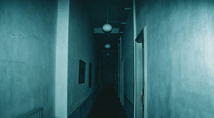 Dark narrow hallway with dim lighting, creating a suspenseful atmosphere often seen in worst movie tropes scenes.