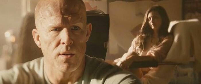 Man with a scarred face in the foreground and a woman sitting in the background highlighting common worst movie tropes quiz scenes.