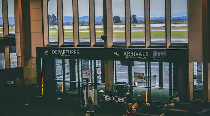 Airport terminal showing departure and arrival signs with travelers waiting, illustrating worst movie tropes quiz theme.