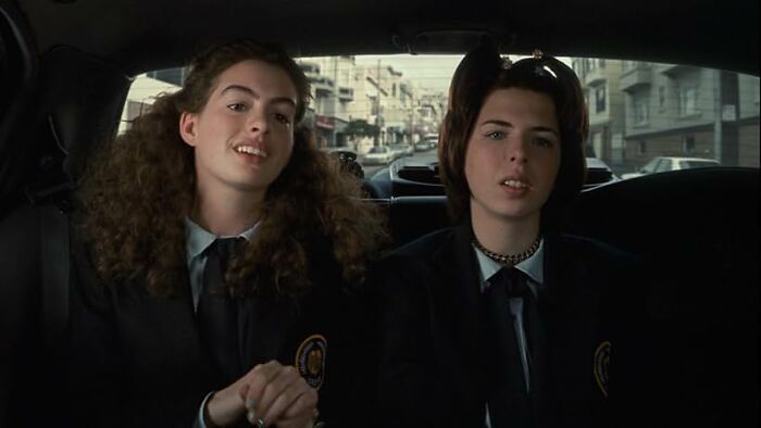 Two young women sitting in a car wearing school uniforms, illustrating a scene for the worst movie tropes quiz.