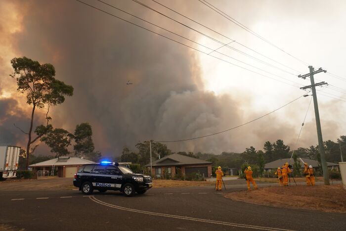 Police vehicle with flashing lights and firefighters monitoring the sky during catastrophic wildfires in recent history.