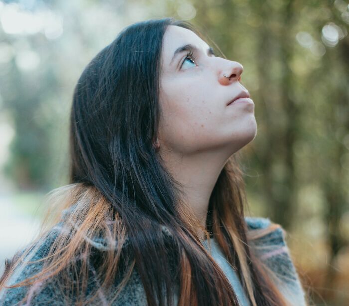 Young woman with long dark hair looking up thoughtfully outdoors, representing rare phobias awareness and reflection. - 5