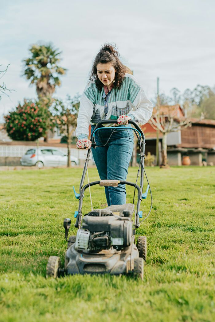 Woman pushing a lawn mower outdoors, symbolizing parents punishing their kids by leaving them alone for days with no food.