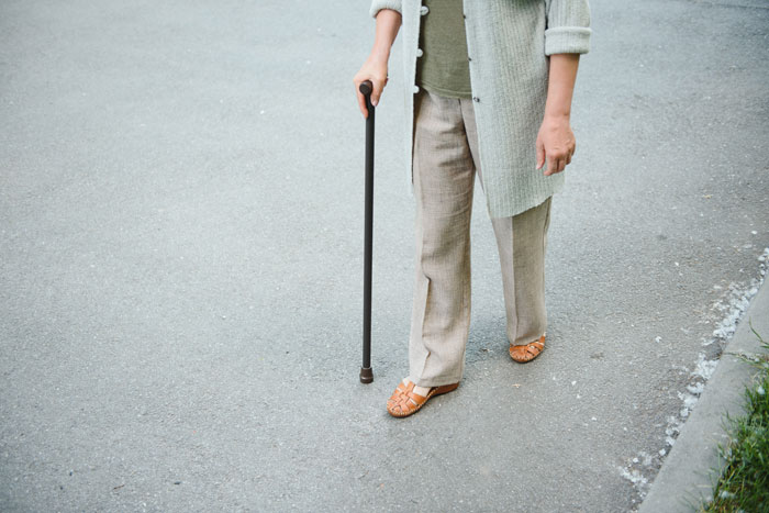 Person using a cane walking on pavement, representing disabled employee facing ableist manager challenges in workplace accommodations. Person using a cane walking on pavement, representing disabled employee facing ableist manager challenges in workplace accommodations.
